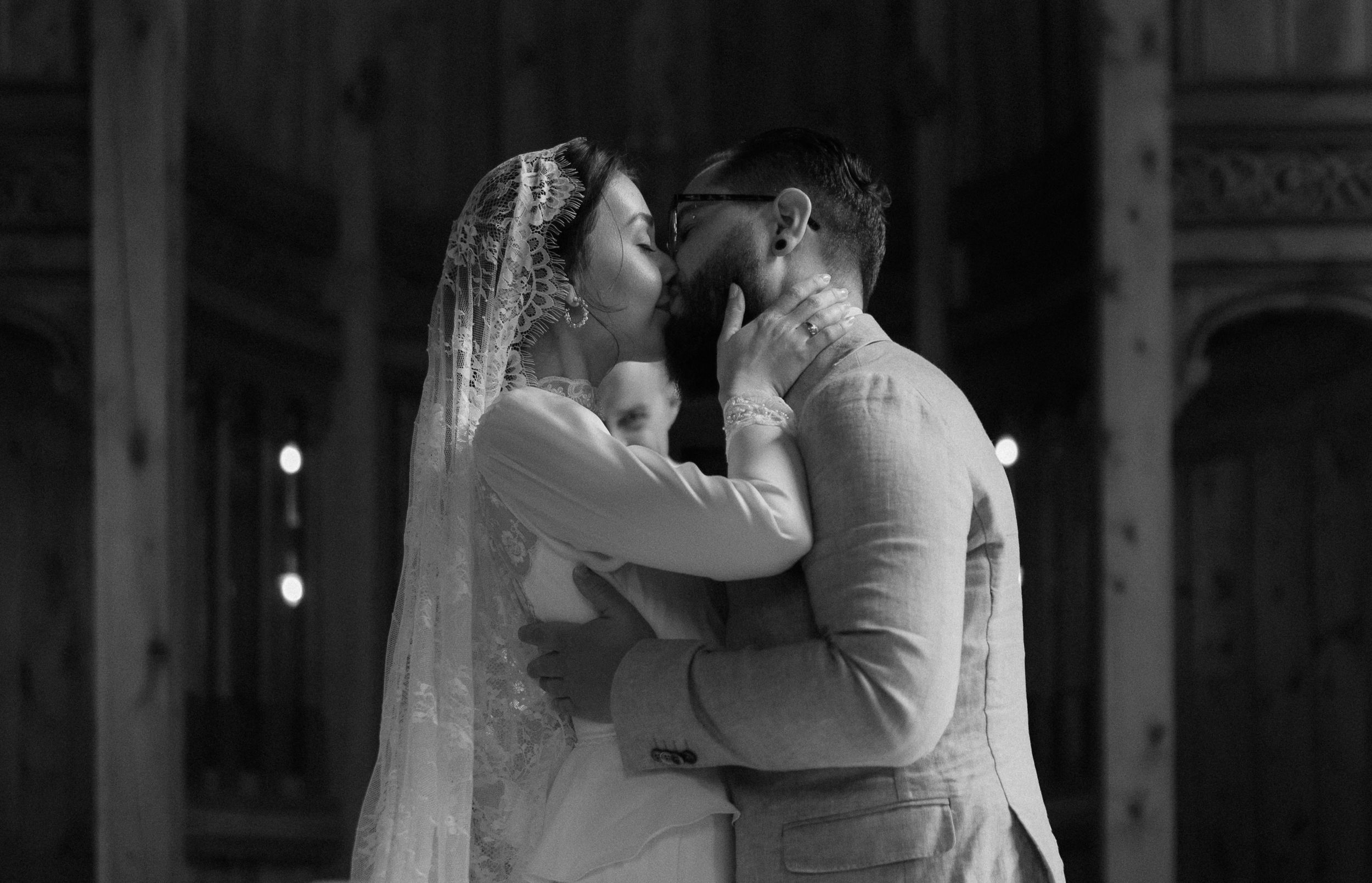 A romantic moment shared between newlyweds in a dimly lit historic chapel space.