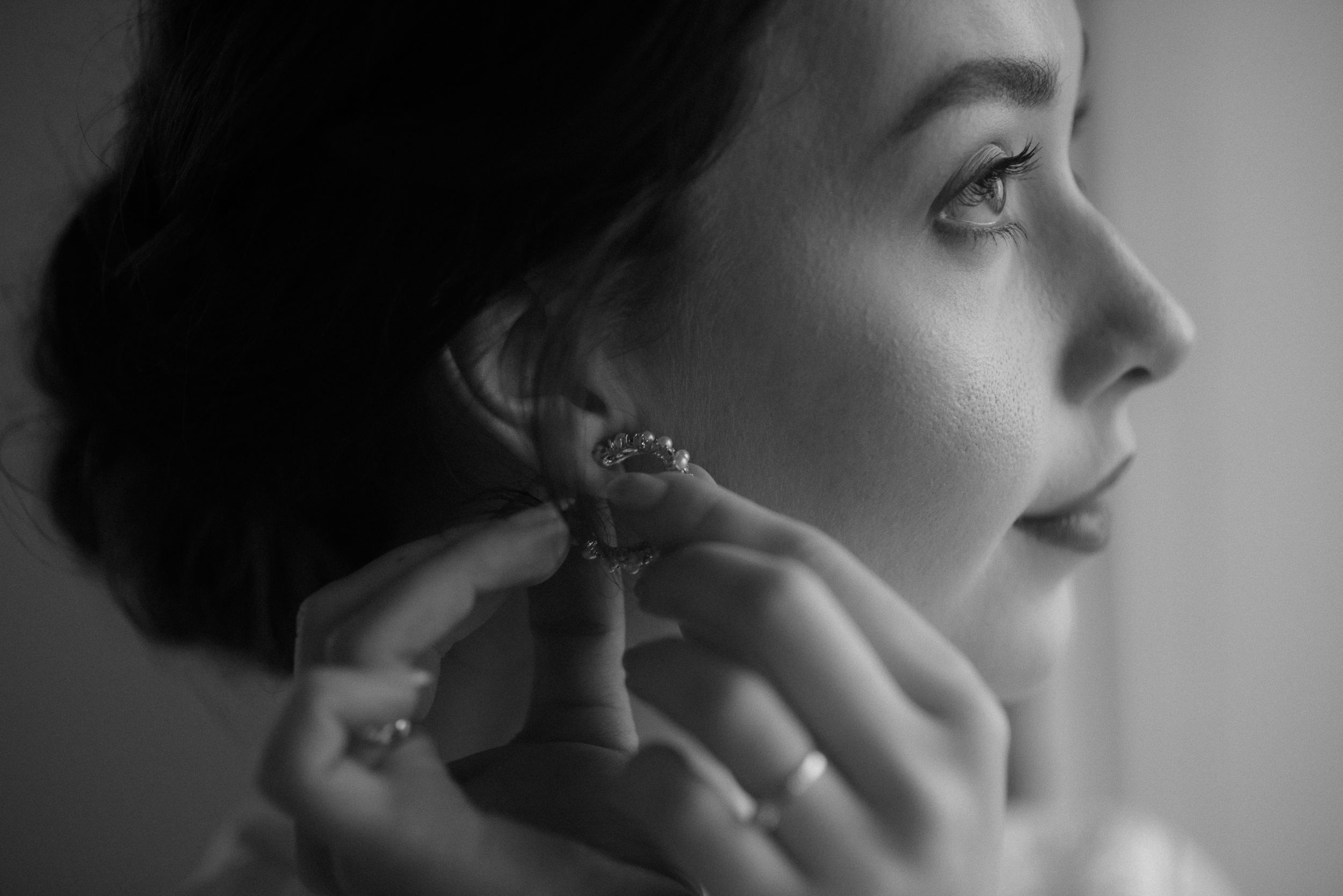 Artistic black and white profile portrait with focus on jewelry and styling.