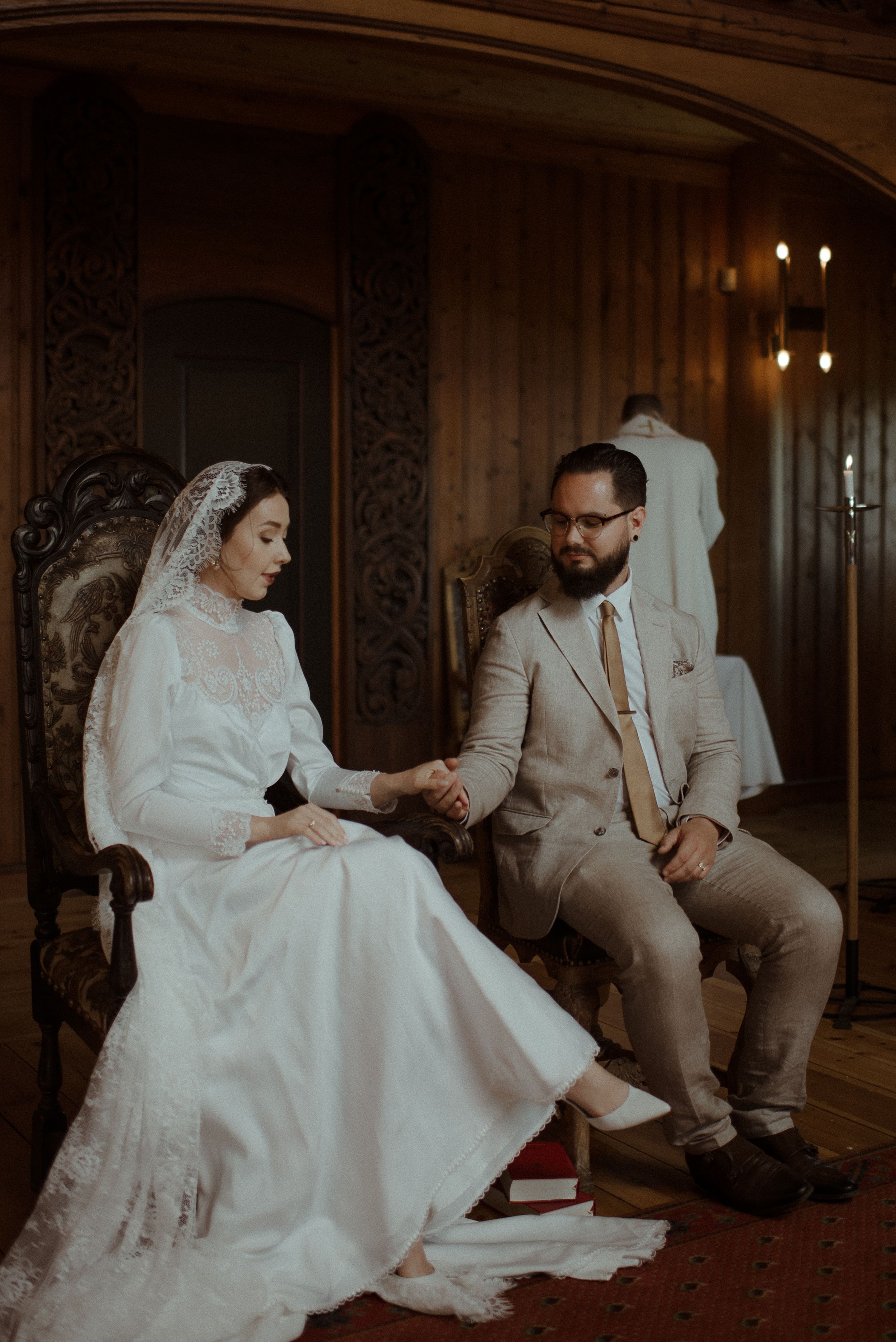 A vintage-inspired wedding portrait in an ornate wooden chapel with antique furnishings.
