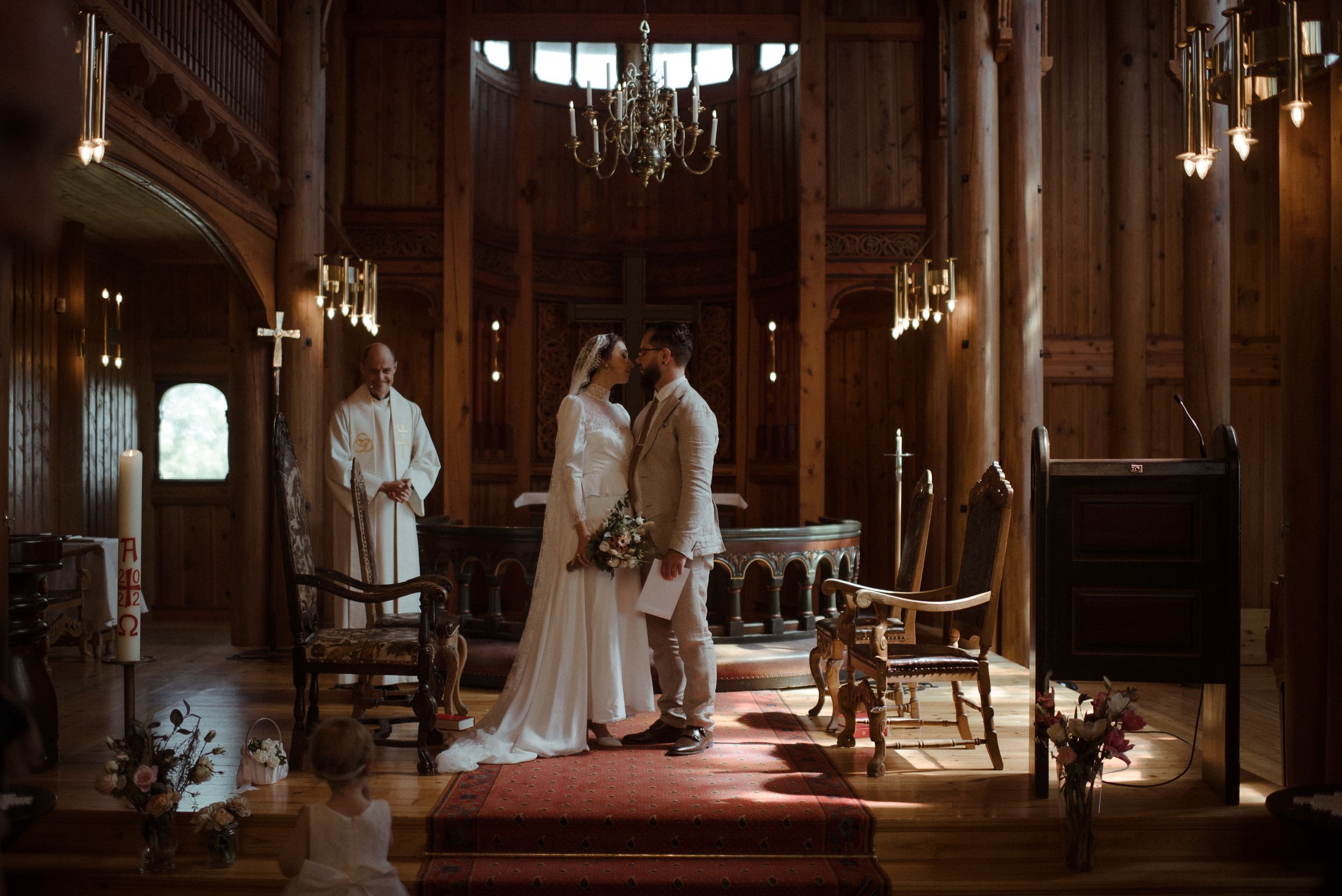 A wedding ceremony in a historic church with wooden panels and elegant chandeliers.
