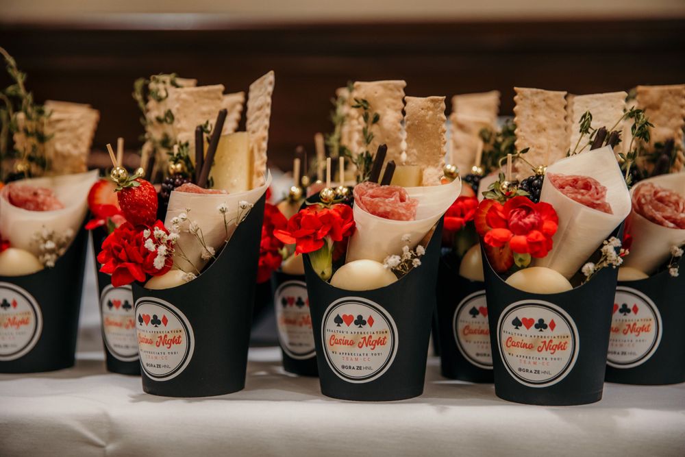 Small black cups with red flower bouquets and paper wraps arranged in a row for an elegant event display.
