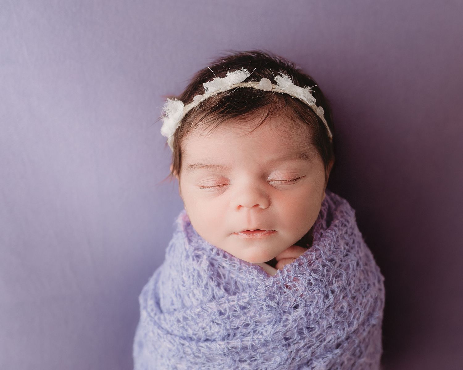 professional photo of a newborn baby wrapped in purple