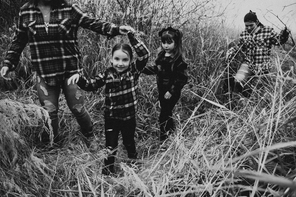 Black and white photo of people exploring through tall prairie grass.