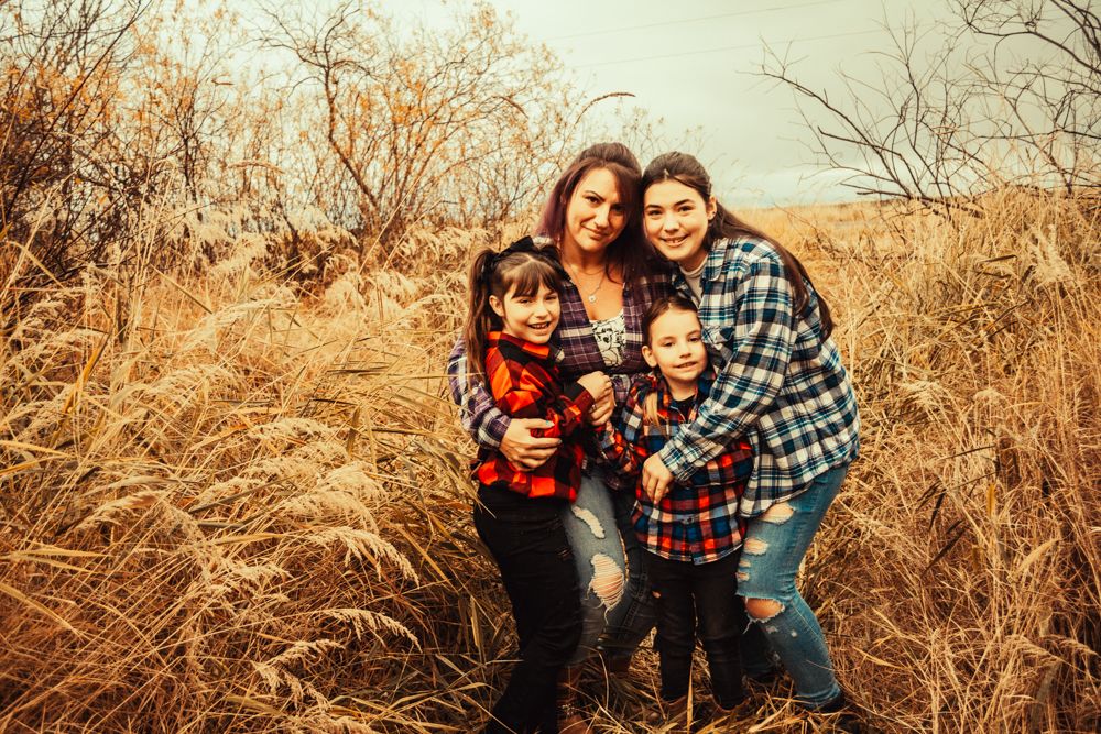 A group wearing coordinated plaid flannel shirts huddles together for a photo in autumn grass.