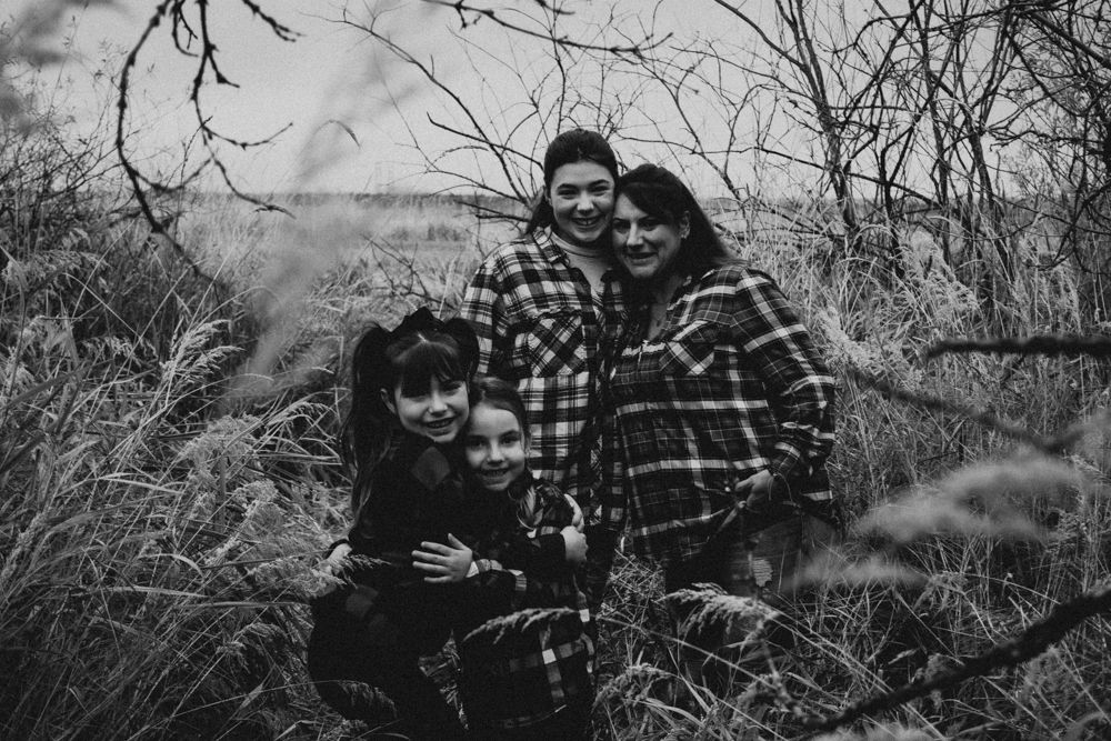 Group portrait among wild grass and bare winter branches in monochrome.