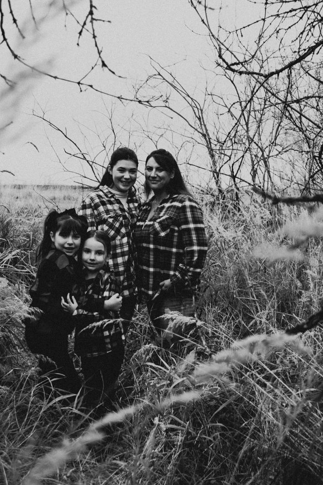 Black and white family portrait taken outdoors in tall grass.