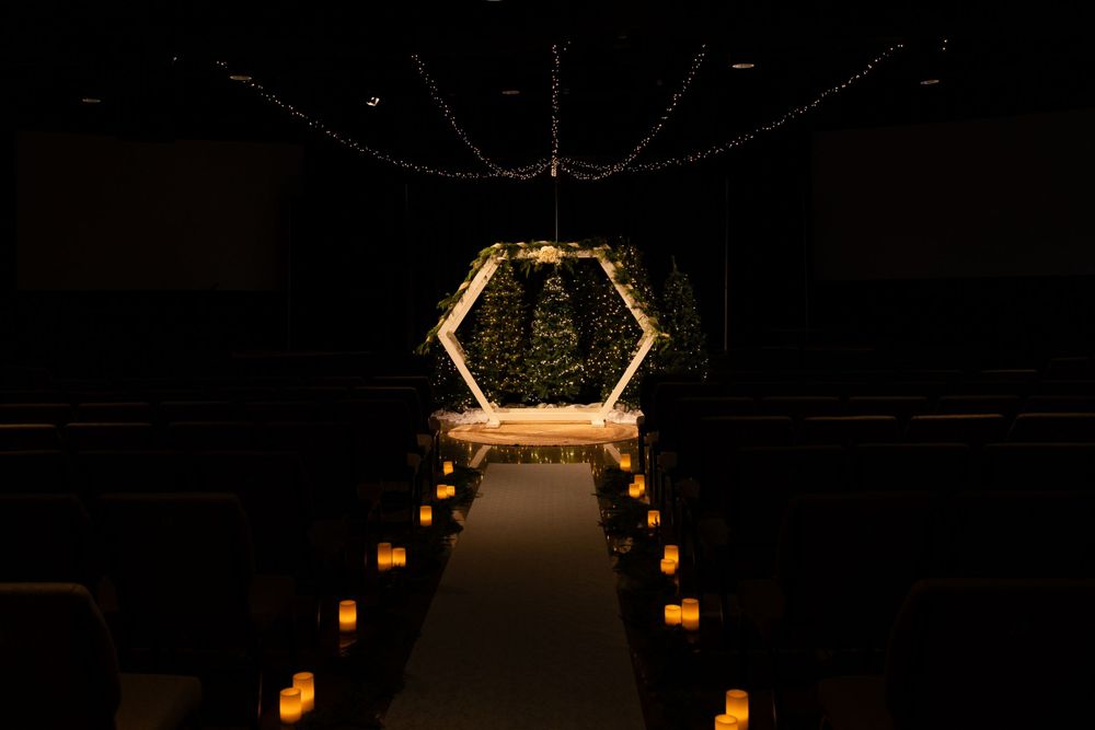 A dimly lit wedding aisle with lanterns leading to a glowing hexagonal arch at the end of the path.