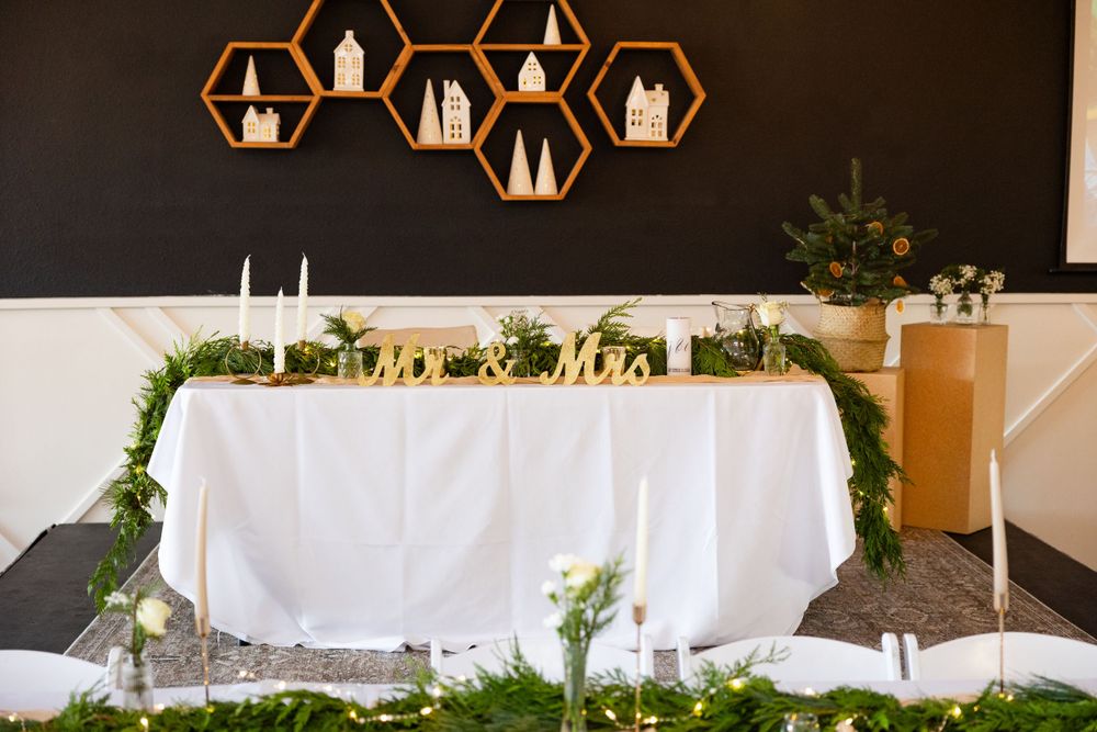 Modern wedding reception table setup with hexagonal light fixtures and greenery decorations.