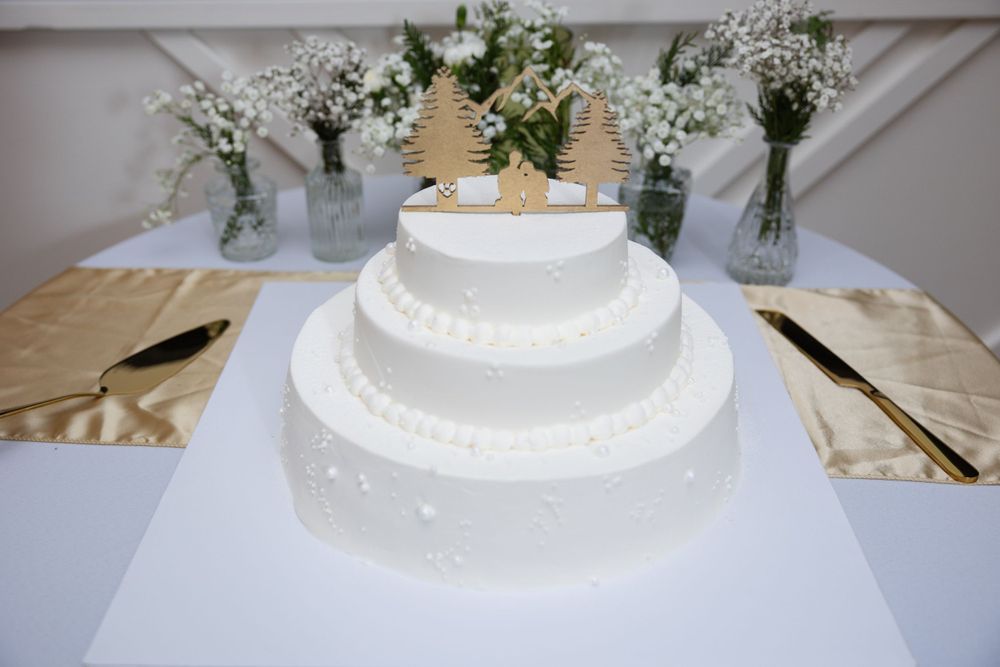Elegant three-tier white wedding cake decorated with baby's breath flowers and gold accents.