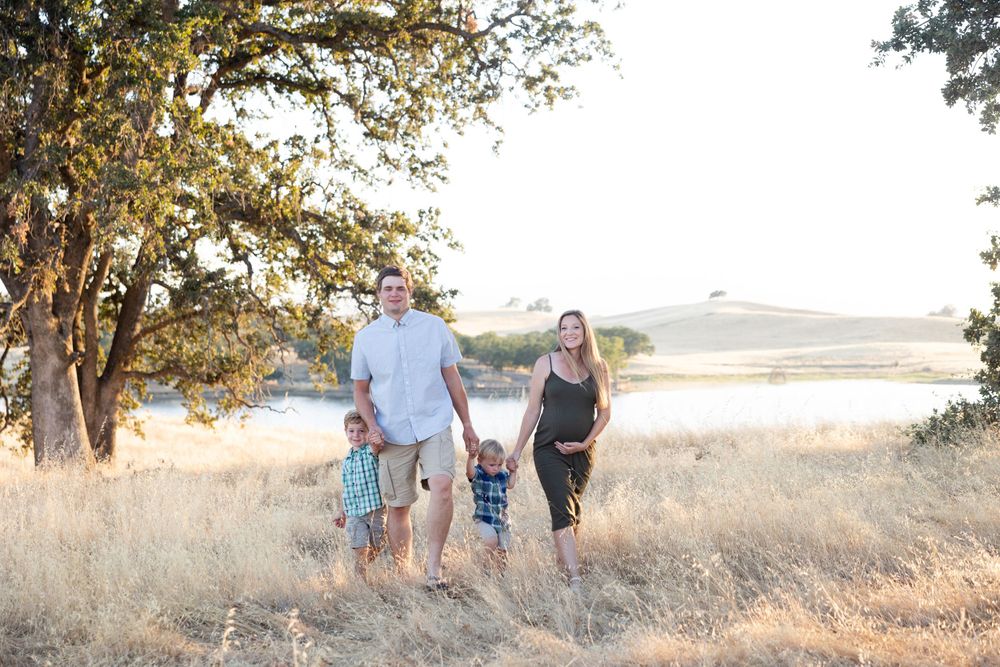 Group enjoying a peaceful walk together through golden grass and trees at sunset overlooking a meadow landscape.