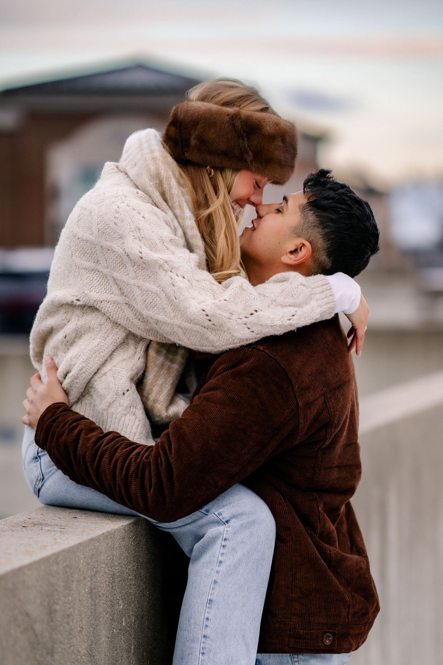 A romantic couple sharing a tender kiss outdoors while wearing cozy winter attire.