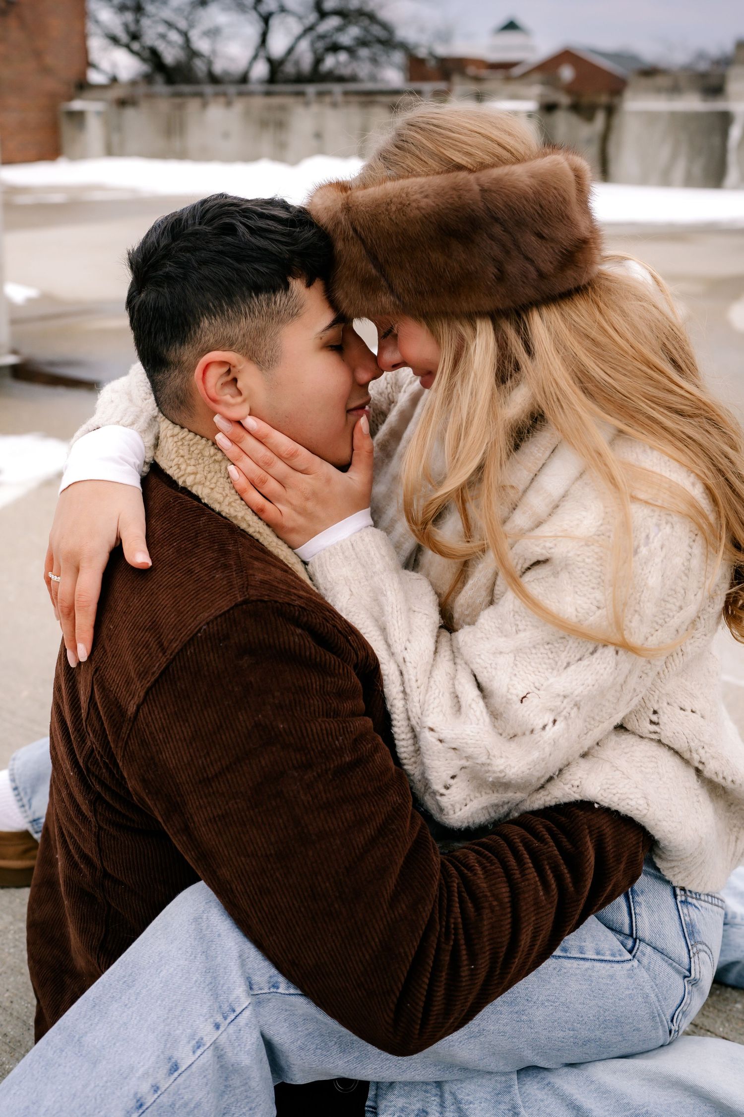 An intimate winter moment showing a couple in warm clothing sharing a tender moment outdoors.