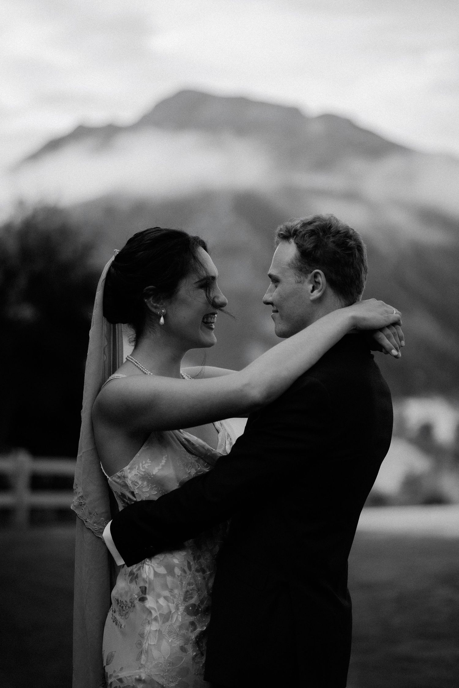 Black and white intimate portrait of a bride and groom sharing a tender moment together outdoors.