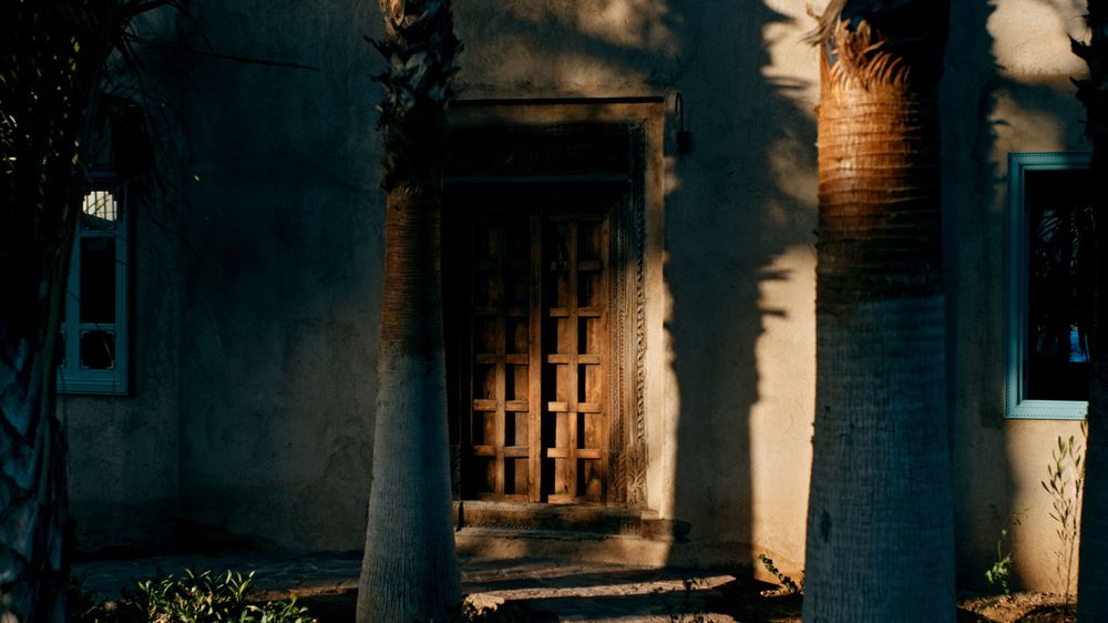 Dark archways and stone columns create dramatic shadows in a historic Mediterranean courtyard at dusk.