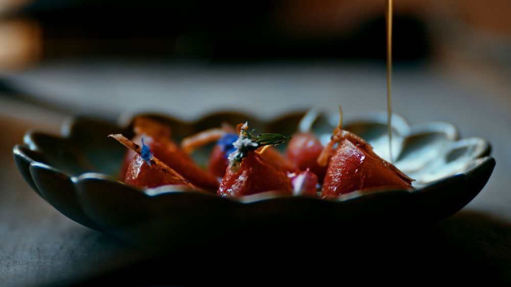 Fresh strawberries and raspberries arranged in rustic ceramic bowls on a dark wooden surface with natural lighting.
