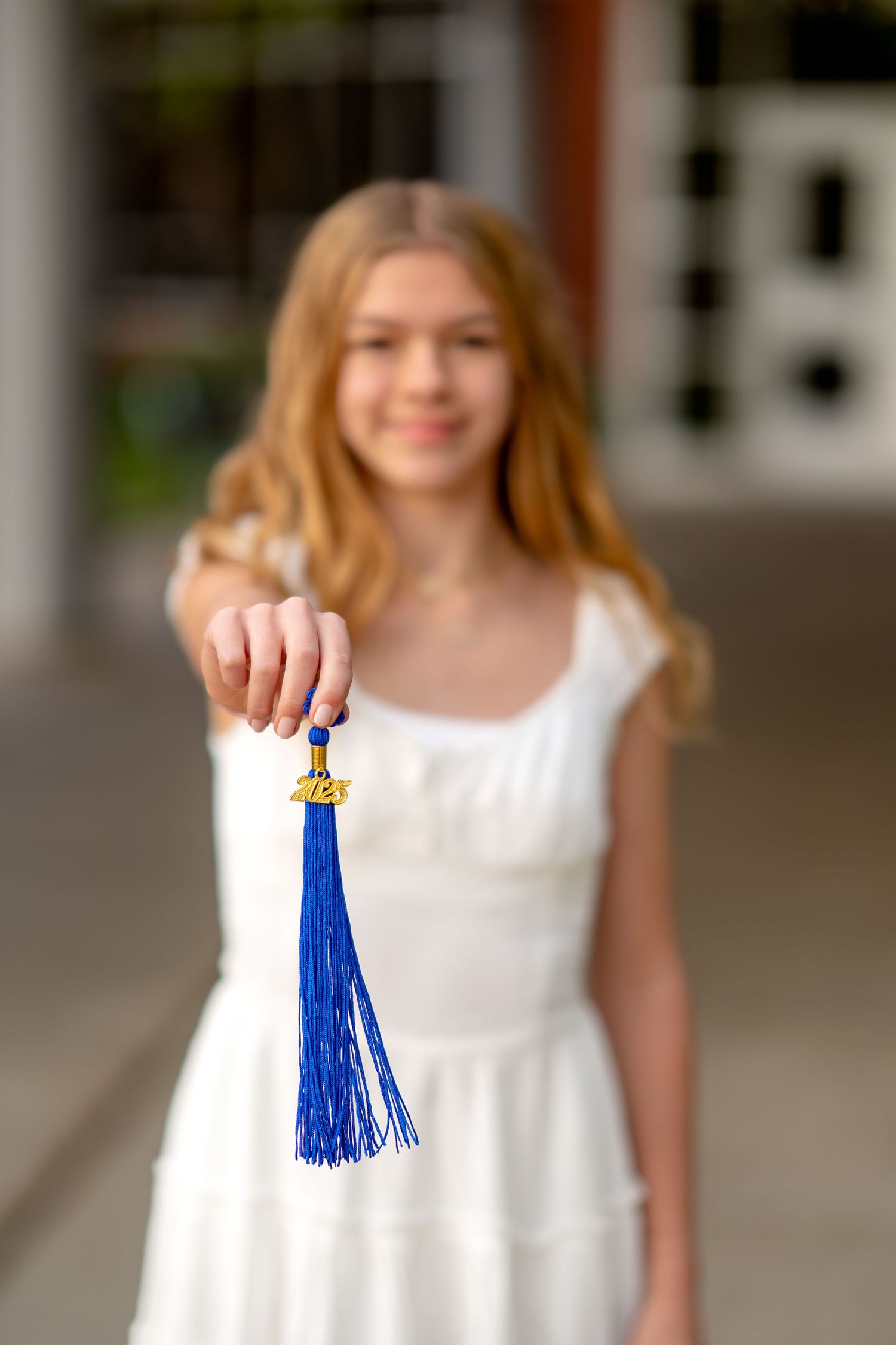 A bright blue decorative tassel with golden accents hangs suspended against a blurred background.