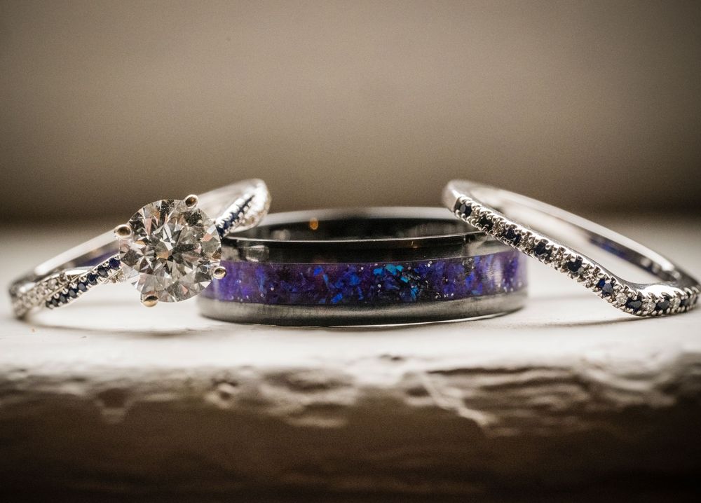 Close-up details of sparkling wedding rings and jewelry accessories arranged on a neutral surface.
