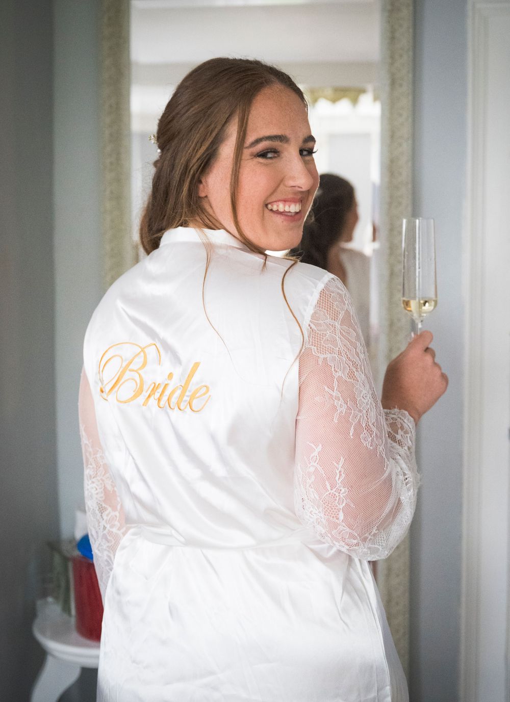 White satin bridal robe with lace detailing and gold 'Bride' embroidery on the back.