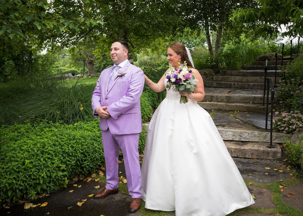 Wedding couple walking through a garden path with lavender and white attire.