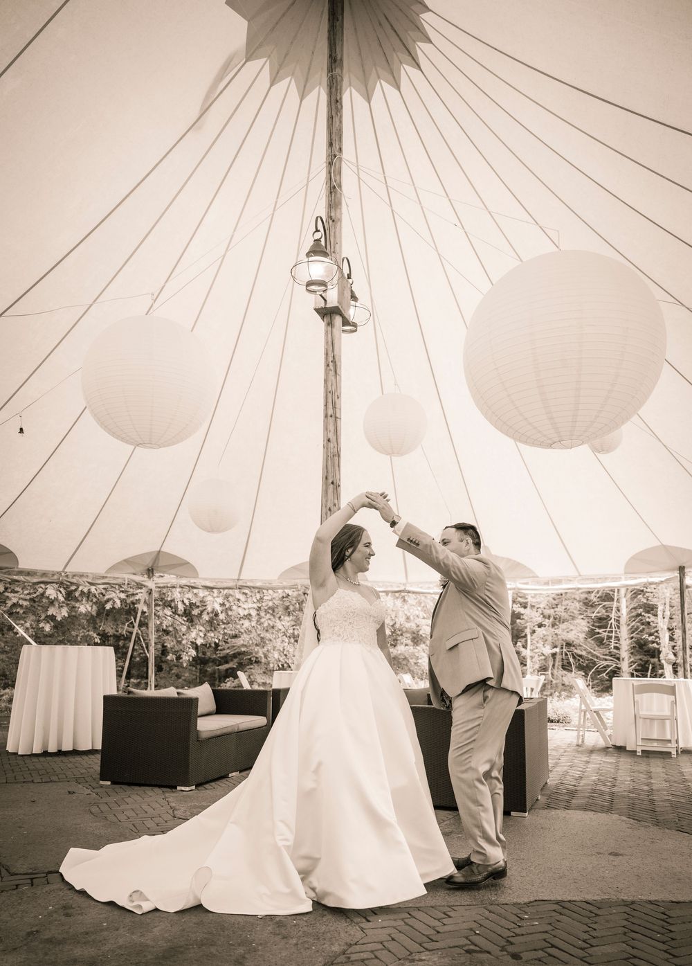 A wedding couple dancing in a white tent pavilion, captured in a sequence of four black and white photos.