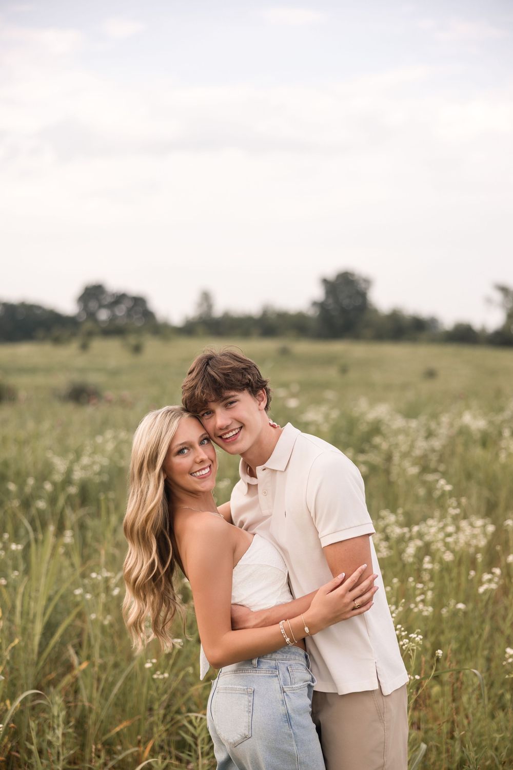 Romantic couple embracing and laughing together in a wildflower meadow during golden hour.
