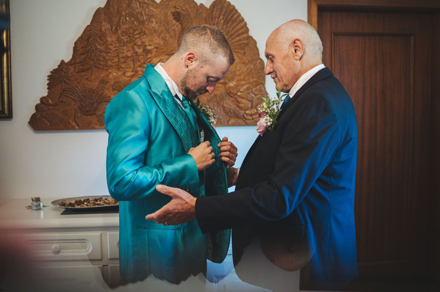 Indoor wedding preparation scene with turquoise and navy blue formal attire.