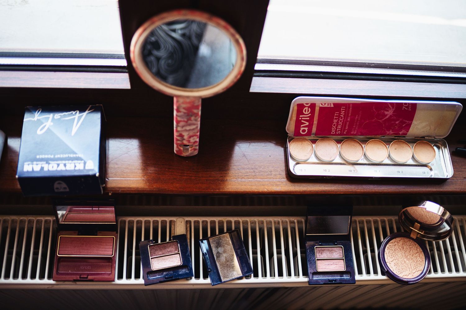 Vintage vanity with oval mirror displays makeup and beauty products neatly arranged.
