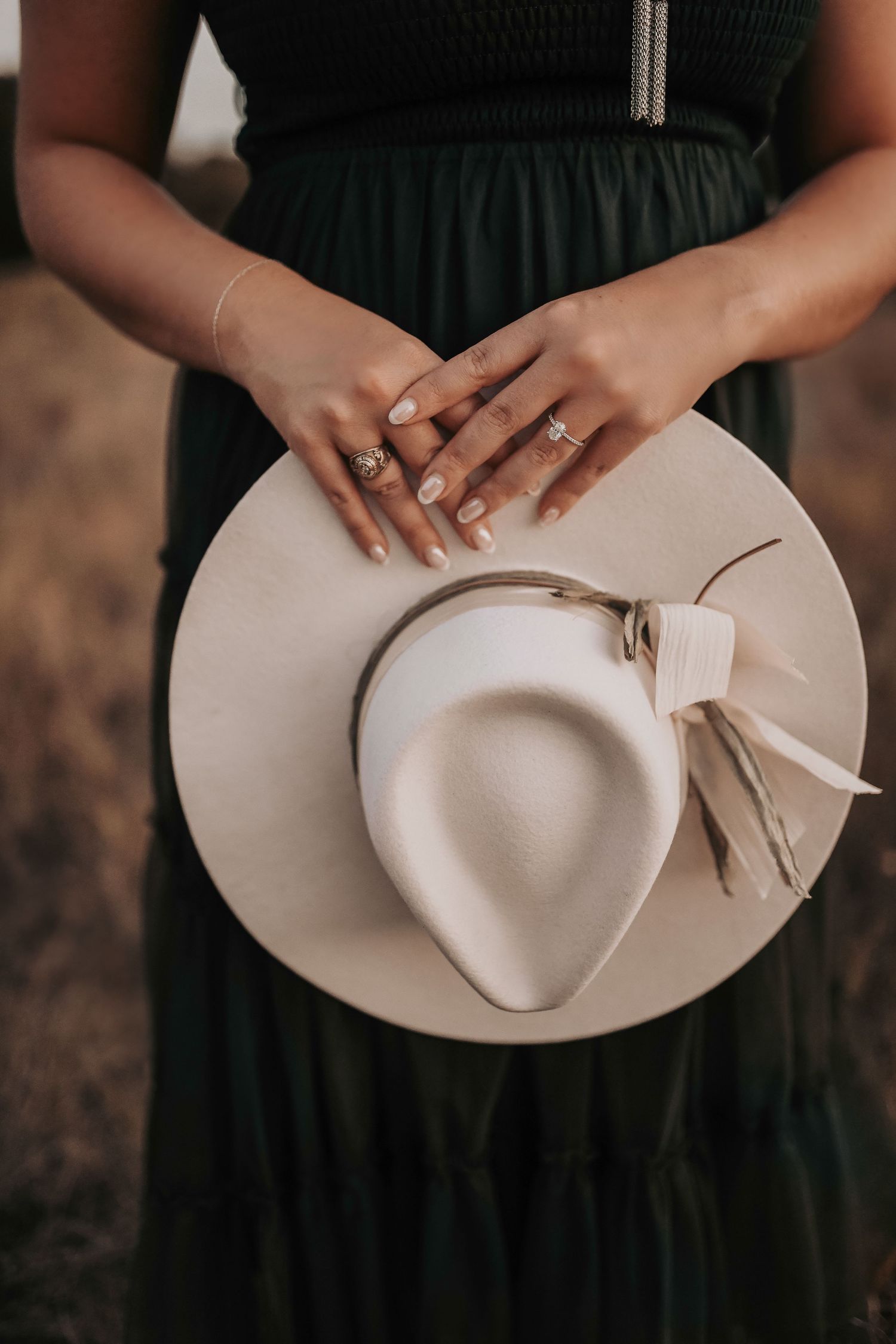 close up of a fiance holding her cowgirl hat showing off her class ring and her engagement ring