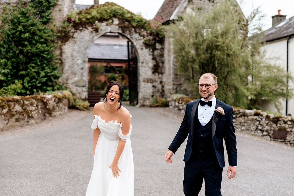 A couple walk together on a rustic stone pathway surrounded by nature.