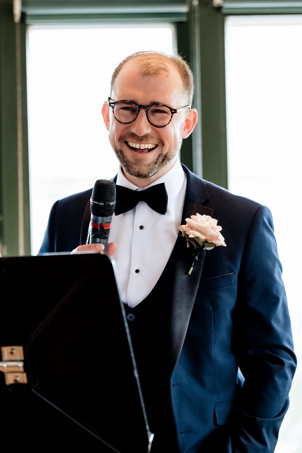 A person wearing a navy tuxedo and bowtie at a wedding celebration.