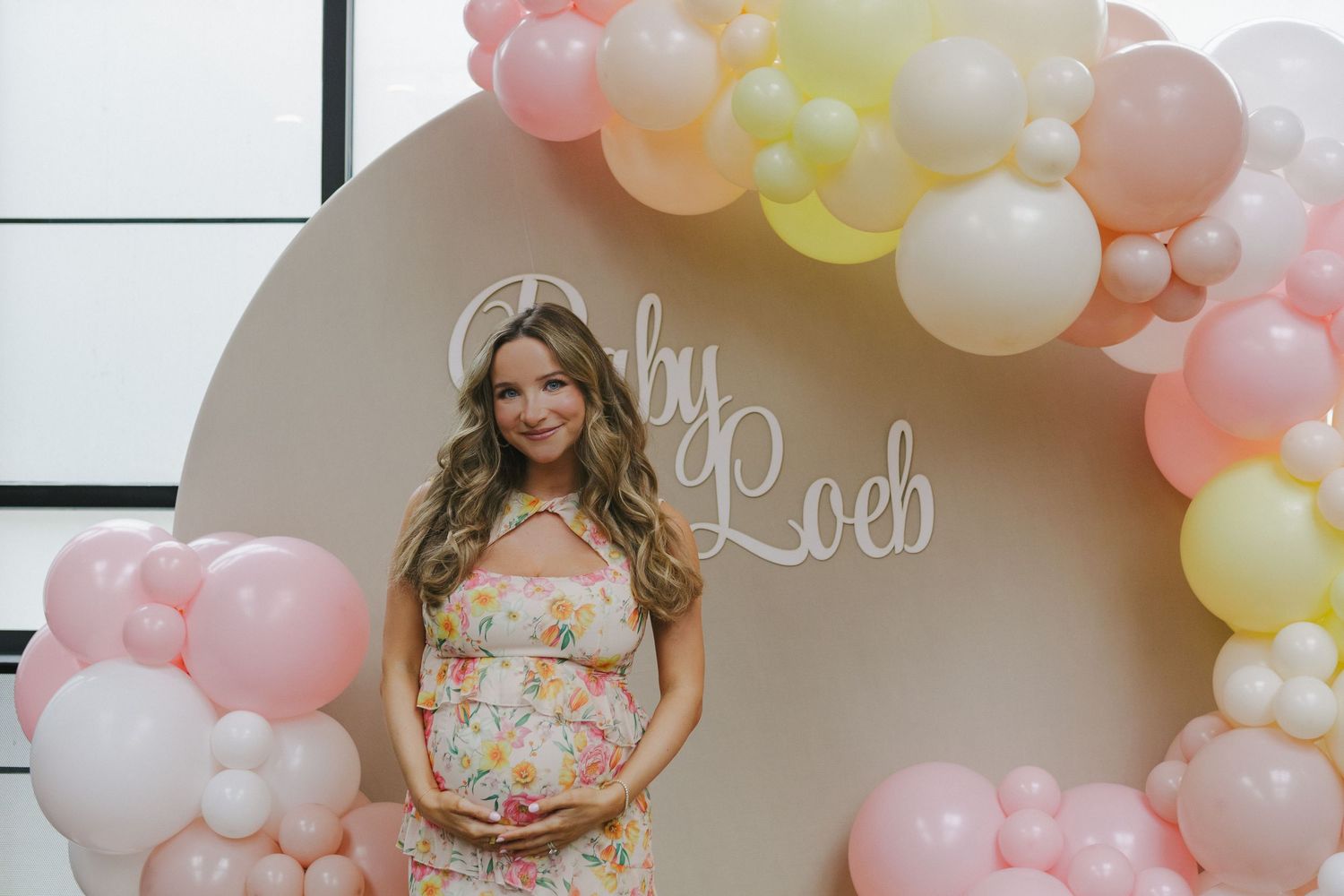 Mom-to-be glowing in a pink floral dress at Brooklyn Winery, captured by NYC baby shower photographer Paula Brearley
