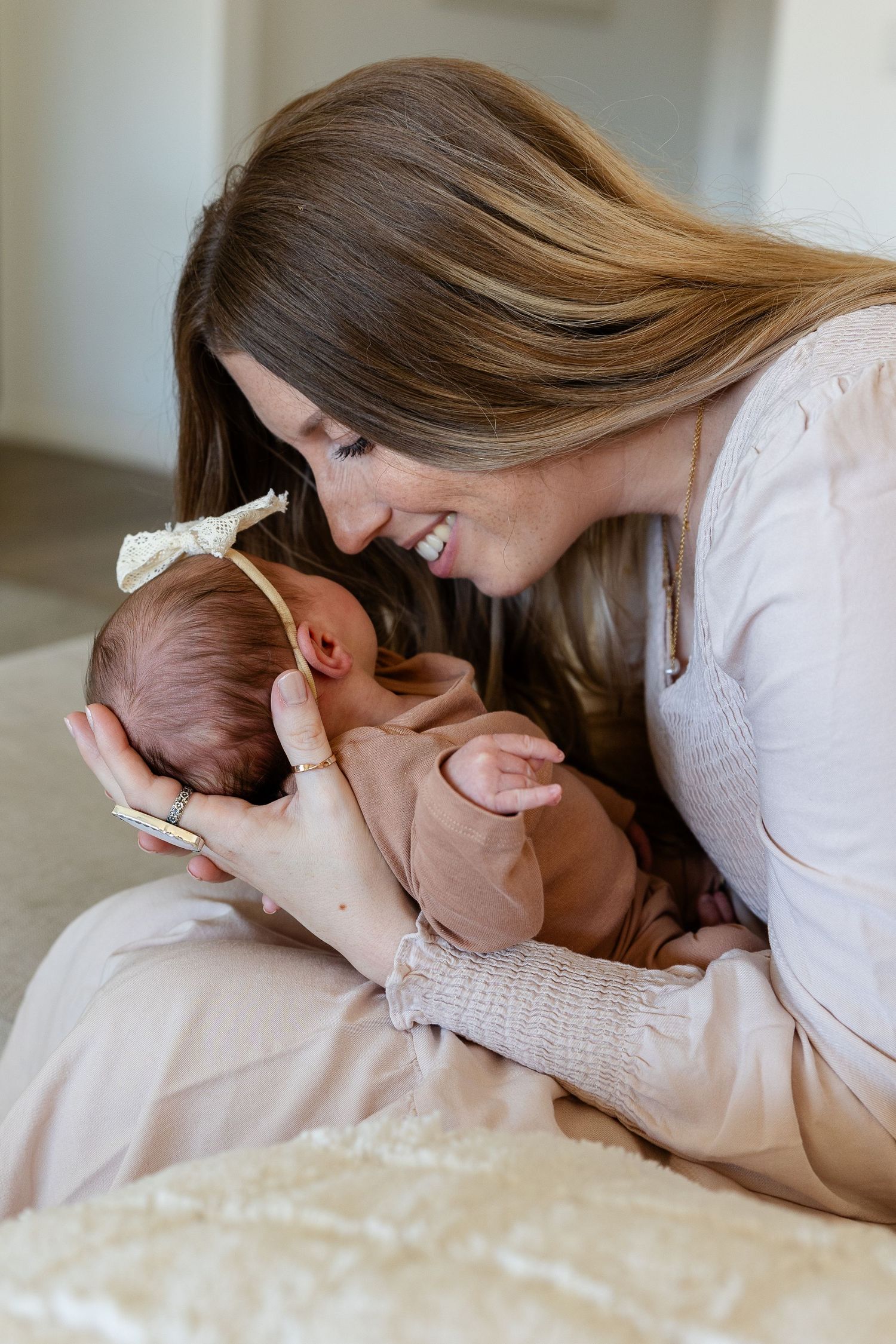 Mom holding newborn smiling nose to nose.