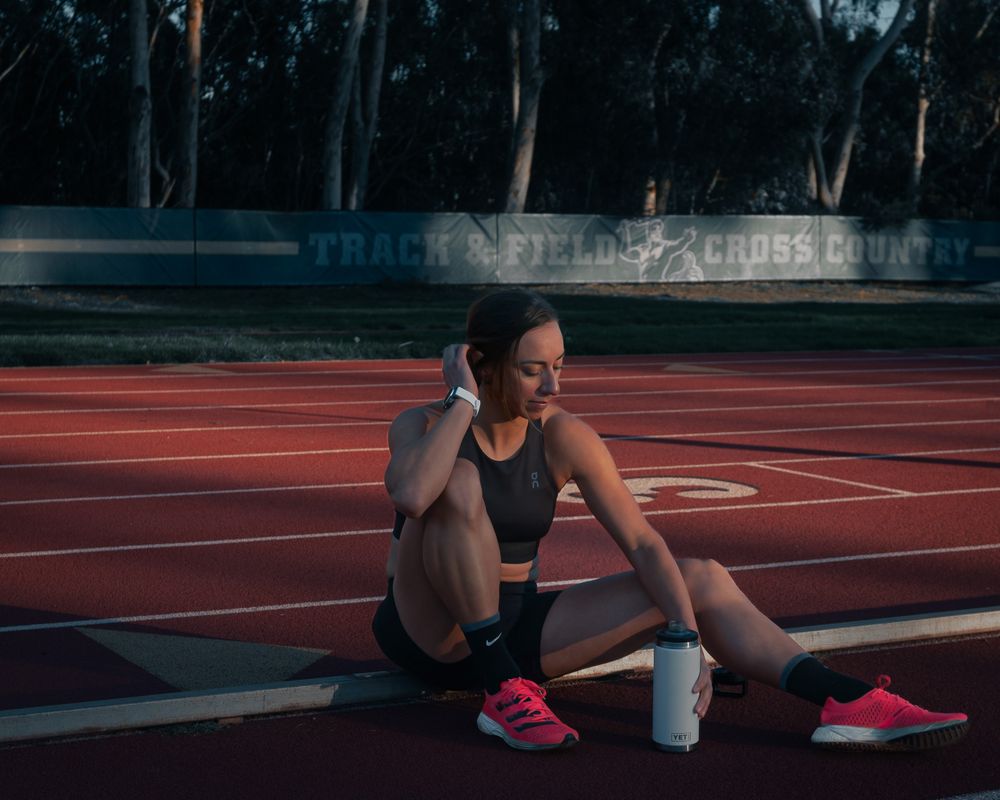 An athlete rests on a red running track during sunset. Brand photography, San Diego, California