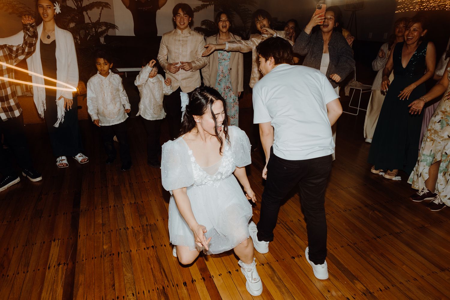 Lively dancing at a wedding reception with guests watching from the sidelines.