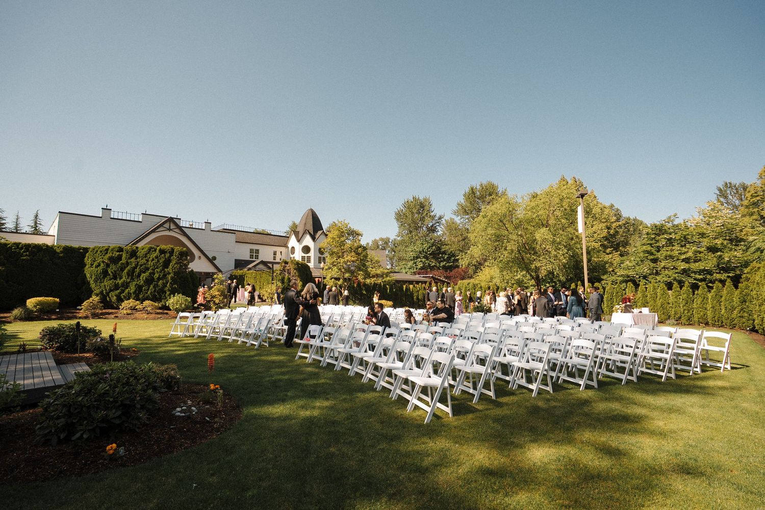 Sets of white folding chairs arranged in rows for an outdoor wedding ceremony under bright sunny skies.