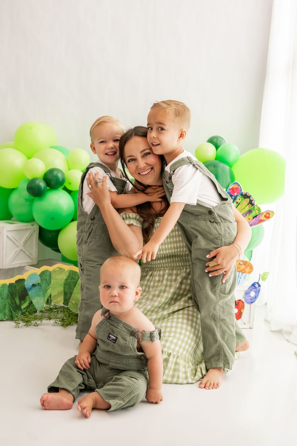 Family portrait session with matching green outfits and balloons showing tender moments between parent and children.