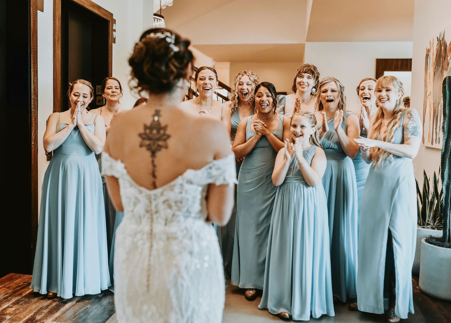 Bridesmaids reacting with surprise and joy seeing bride in wedding dress