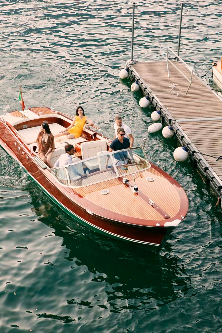 A sequence of photos showing a classic wooden boat approaching and docking at a pier on rippling blue water.