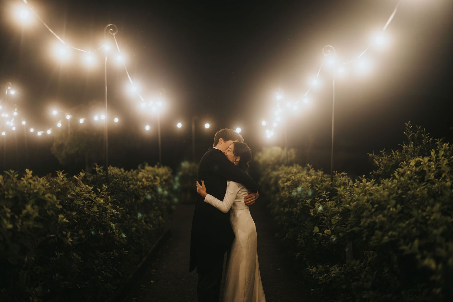 Romantic couple in warm evening light dancing together in an elegant pose outdoors at Askham Hall.