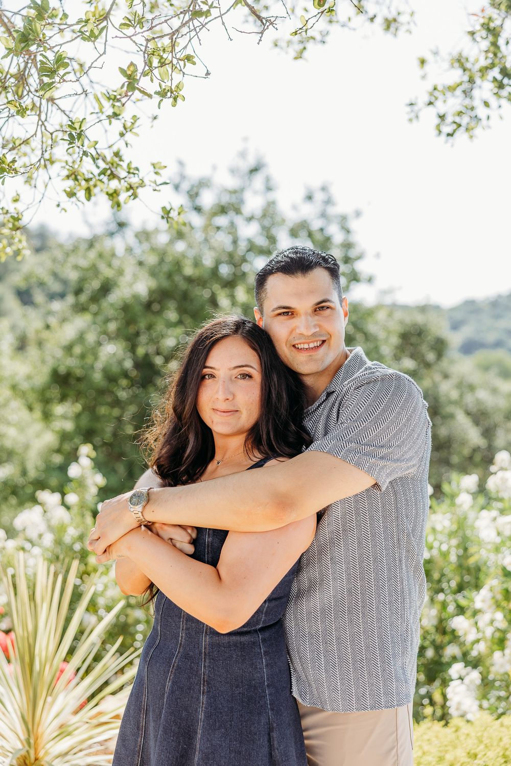 A romantic couple portrait in a garden setting with natural sunlight and greenery.