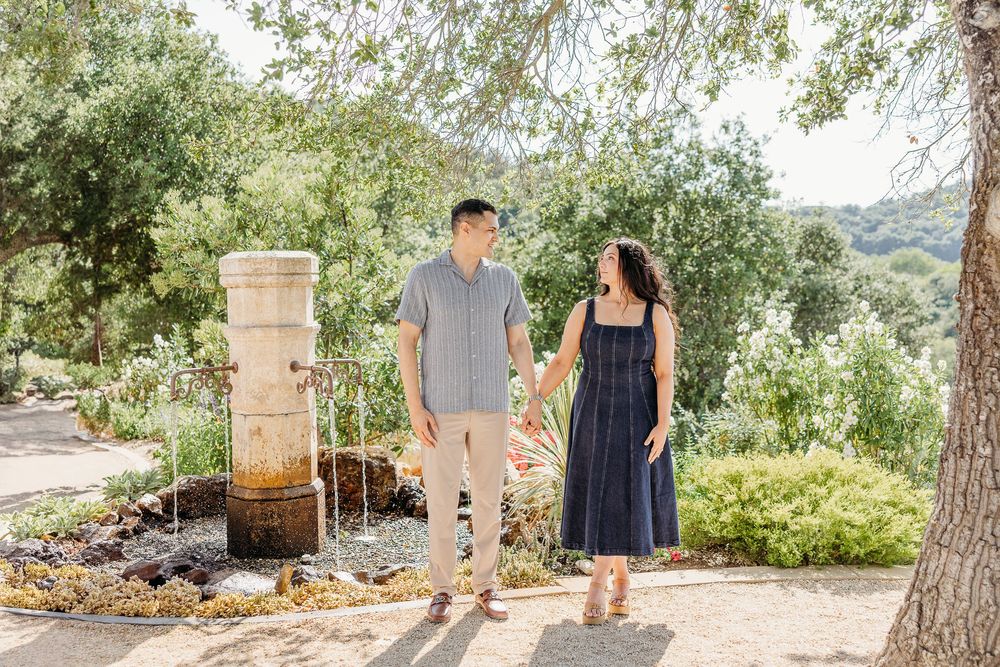 A couple in coordinating outfits walking together in a lush garden setting.