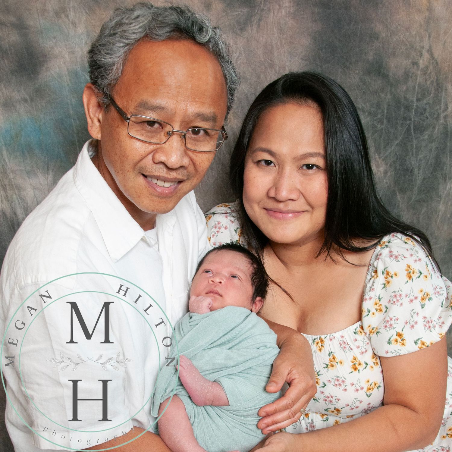 Mom and Dad photo holding newborn wrapped in mint green swaddle.