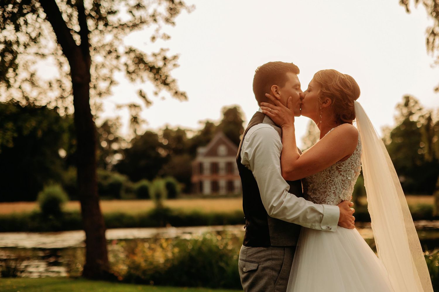 A couple in wedding attire sharing an intimate silhouette moment at sunset in a scenic outdoor setting.