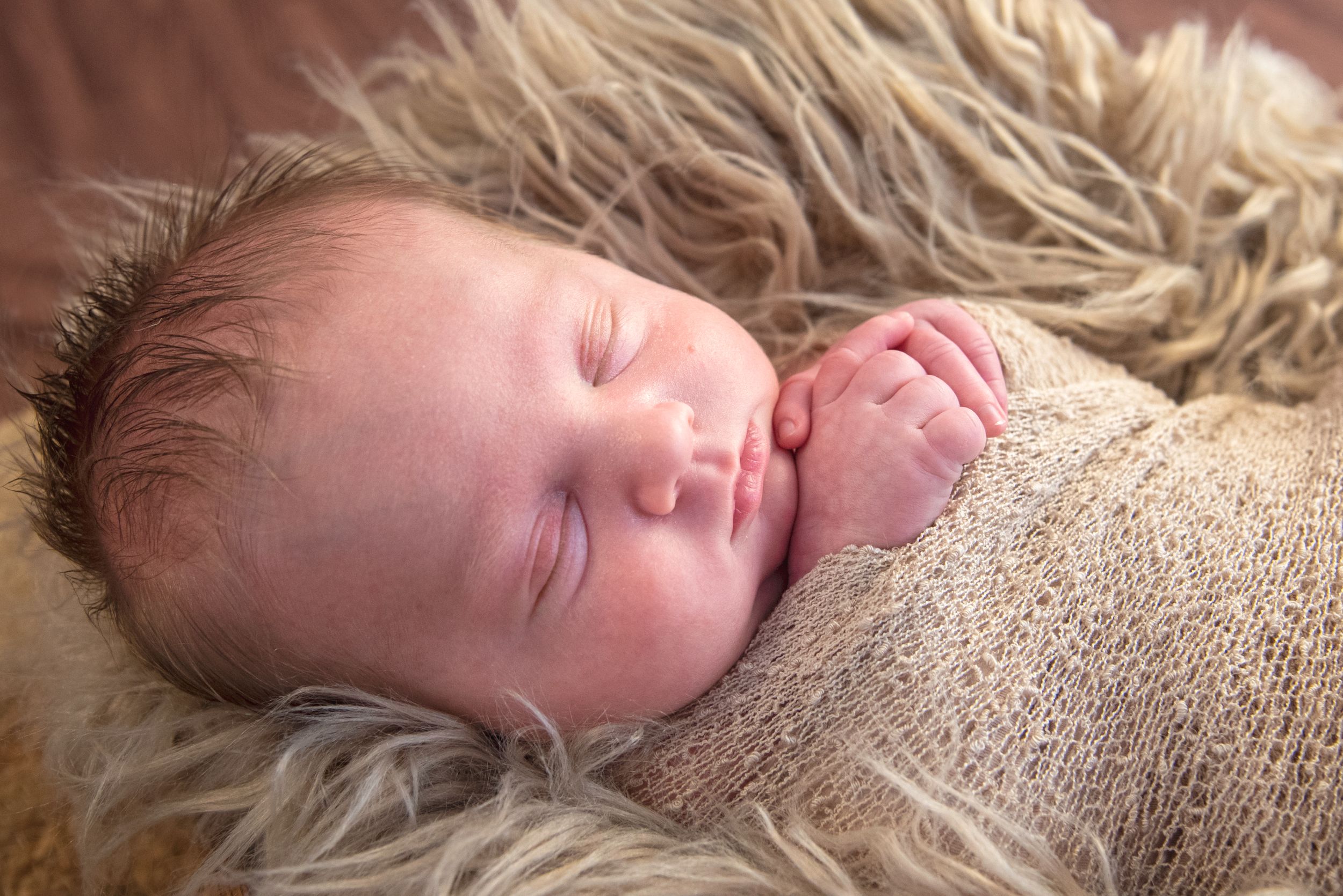 Little Cuddles Photography Adelaide: Newborn photoshoot. Baby wrapped in brown wrap, sleeping in basket with wool rug.