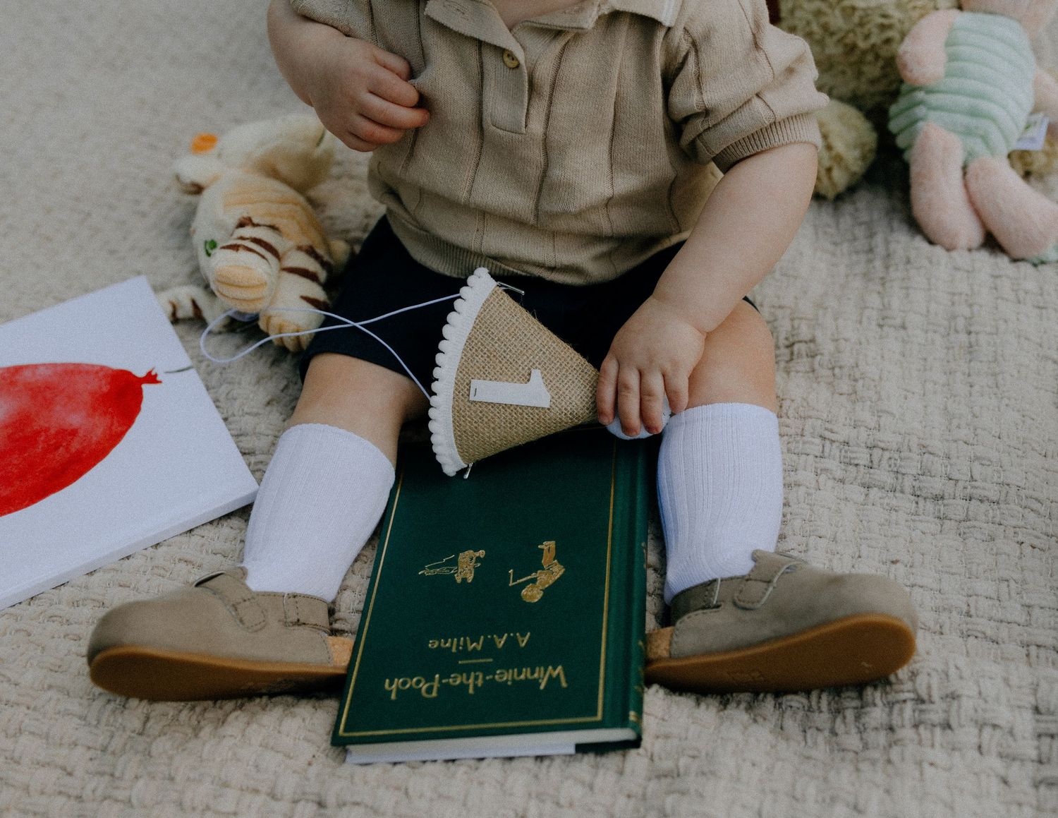 Close-up of small feet in brown shoes with green book on blanket.