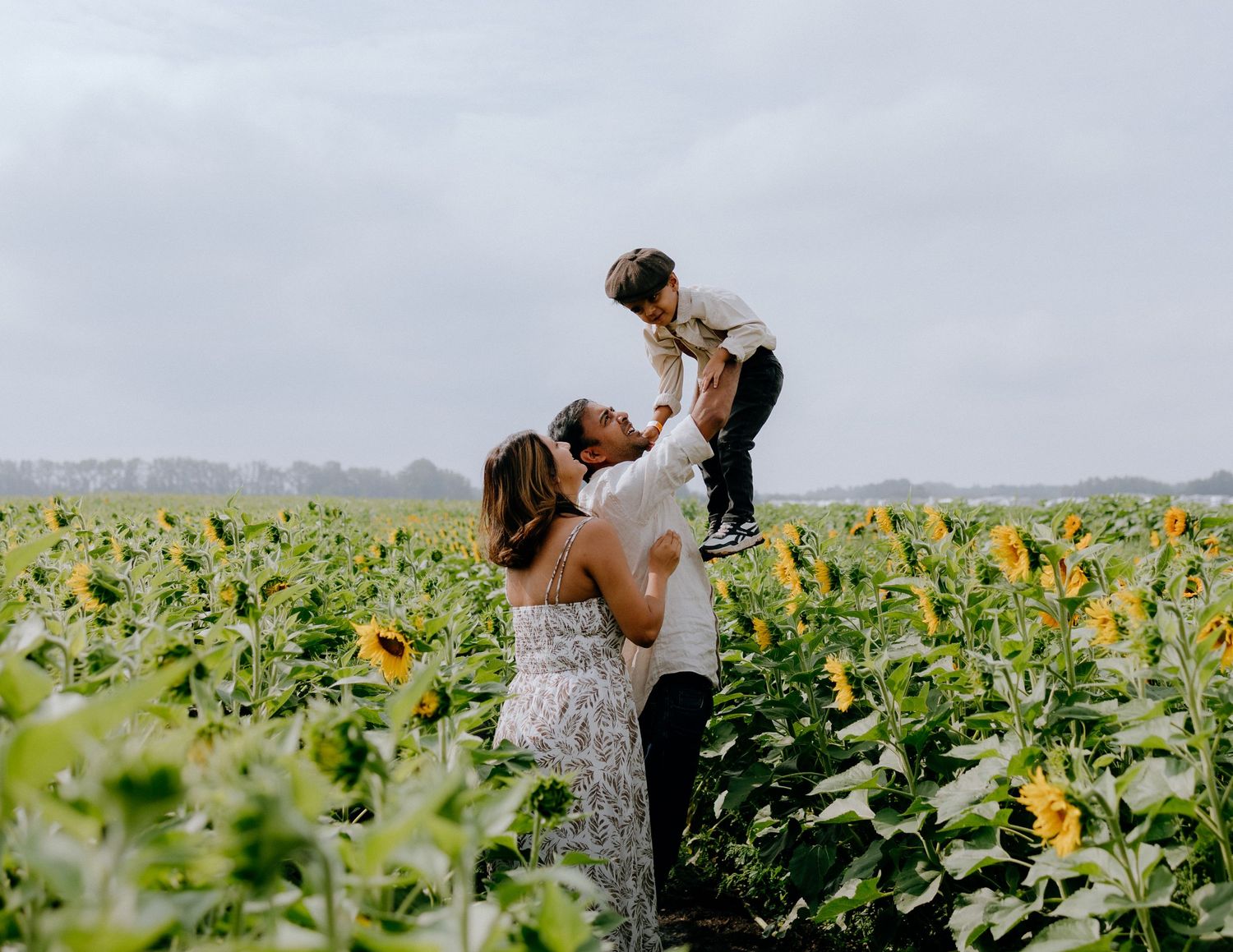A joyful moment captured in a sunflower field with bright yellow blooms stretching to the horizon.