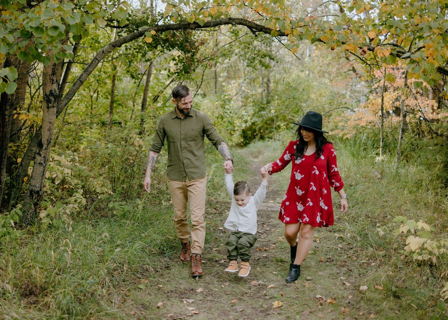 Family walking together on wooded path during autumn.