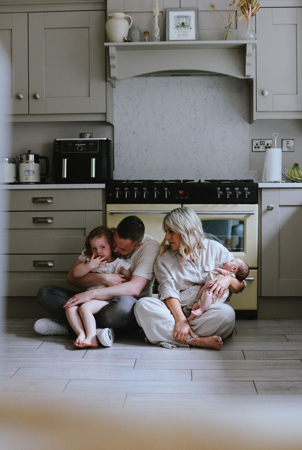 Family sitting together on kitchen floor sharing intimate moments with their children.