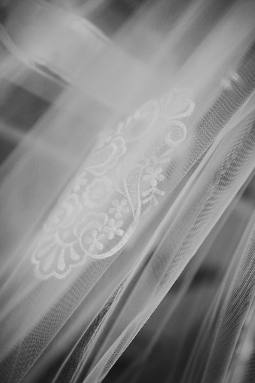 Close-up detail of delicate white floral lace embroidery on sheer fabric in black and white photography Lindley Scott House