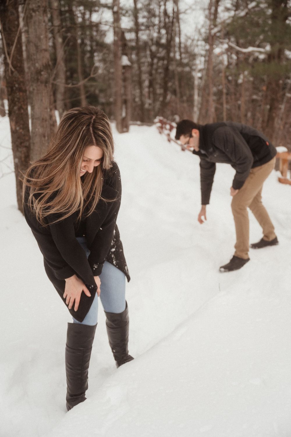 Playful couple having fun throwing snowballs in a snowy winter forest.